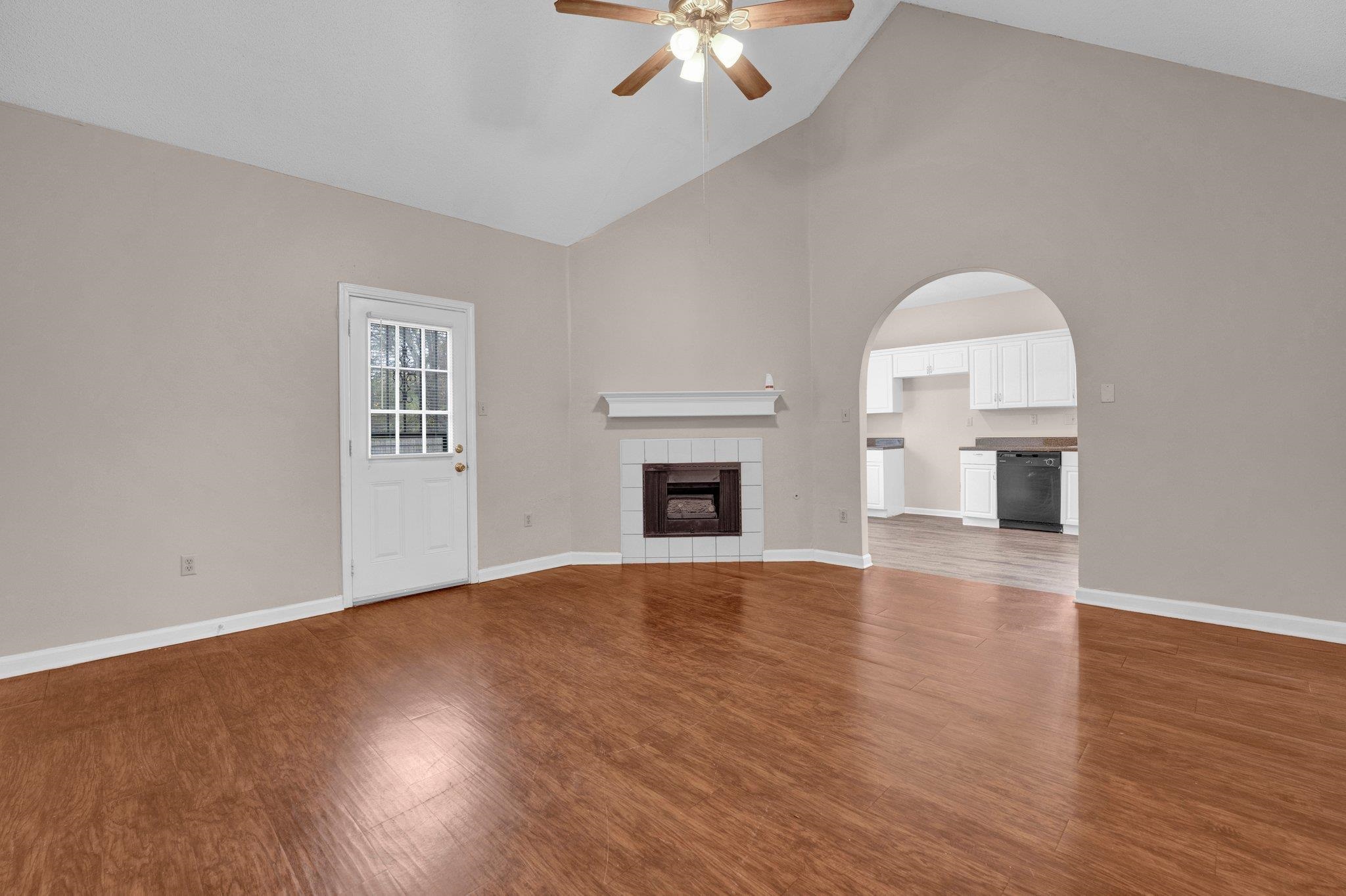 6309 Ragan Farm Drive Memphis, TN 38141 - Photo 8 of 25 Unfurnished living room featuring high vaulted ceiling, a tiled fireplace, hardwood / wood-style flooring, and ceiling fan