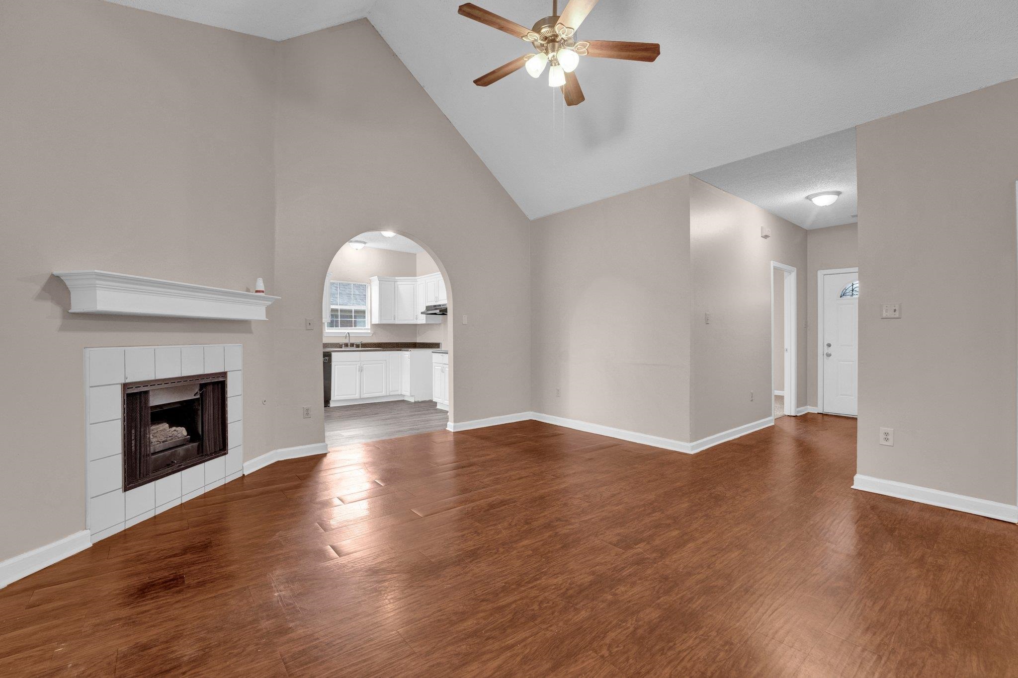6309 Ragan Farm Drive Memphis, TN 38141 - Photo 9 of 25 Unfurnished living room with a fireplace, dark wood-type flooring, ceiling fan, and high vaulted ceiling