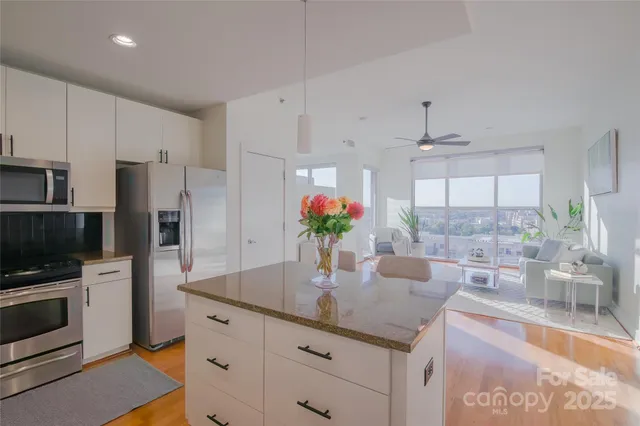 a kitchen with kitchen island granite countertop a sink cabinets and stainless steel appliances