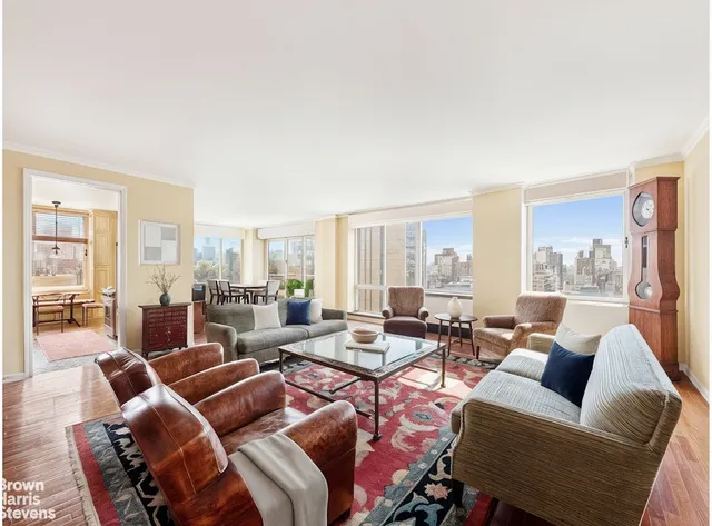 a living room with furniture large windows and wooden floor