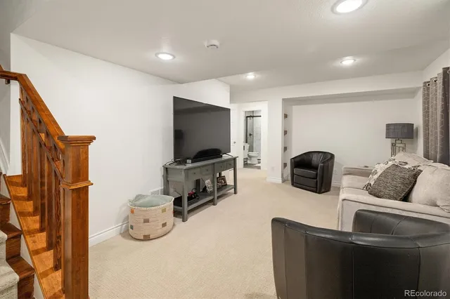 a living room with furniture a flat screen tv and a refrigerator