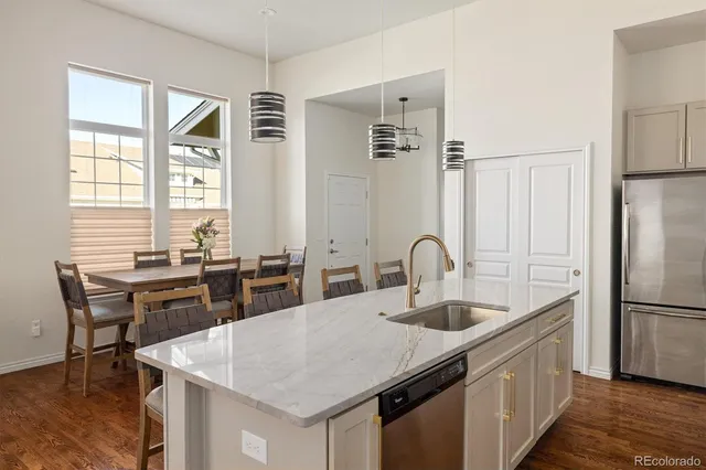 a kitchen with stainless steel appliances granite countertop a table chairs stove and refrigerator