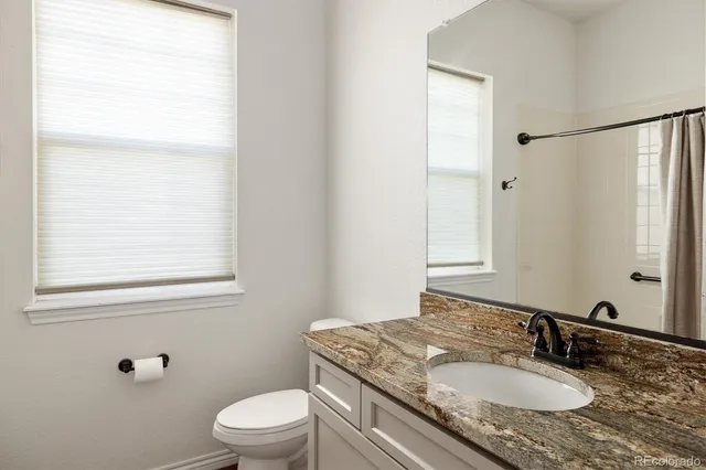 a bathroom with a granite countertop sink toilet a mirror and shower