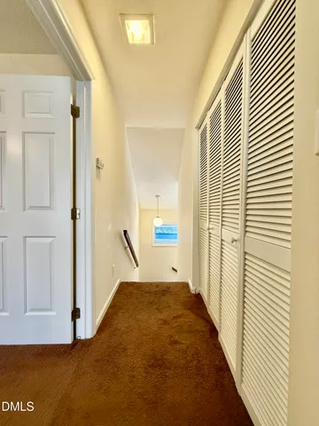 a view of a hallway with wooden floor and a bathroom