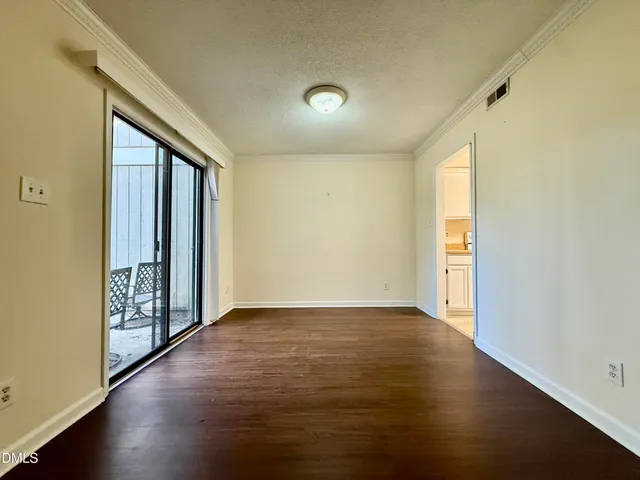 an empty room with wooden floor and windows with curtains