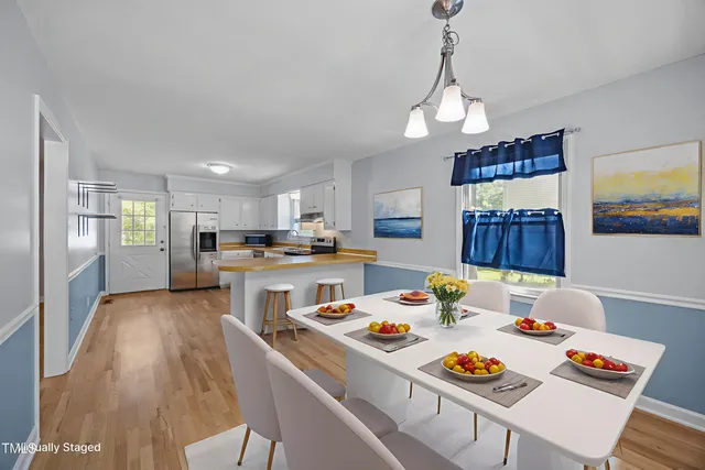 a open dining room with stainless steel appliances furniture a rug kitchen view and a chandelier