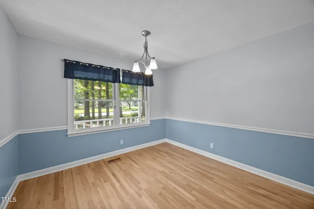 an empty room with chandelier fan and windows