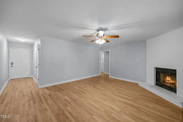 a view of an empty room with wooden floor and a fireplace