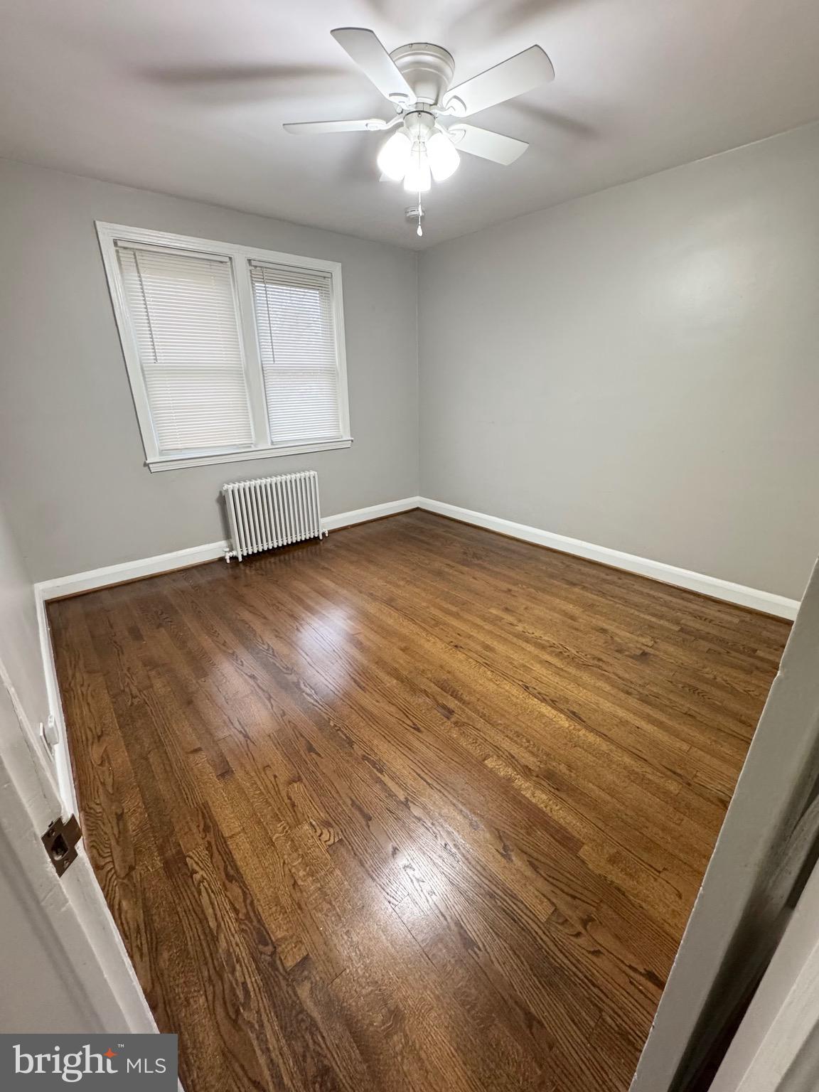 1104 Meridene Drive, Unit 1 Baltimore, MD 21239 - Photo 6 of 7 an empty room with wooden floor fan and windows
