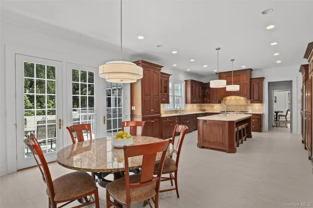 a dining room with stainless steel appliances kitchen island granite countertop a table chairs and a refrigerator