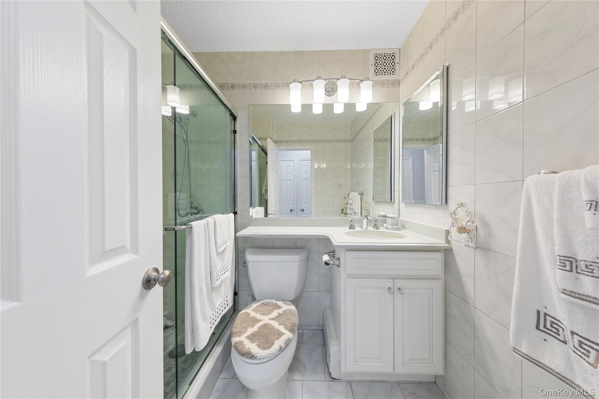 71-28 Sutton Place, Unit 3 Queens, NY 11365 - Photo 16 of 23 Bathroom with tile walls, a stall shower, toilet, and vanity