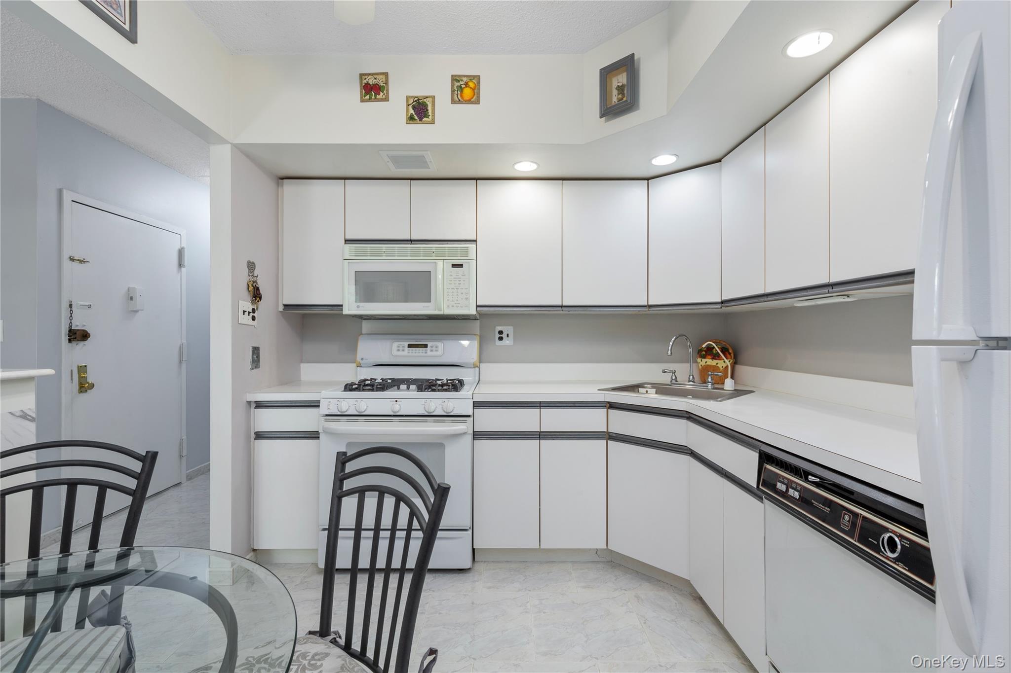 71-28 Sutton Place, Unit 3 Queens, NY 11365 - Photo 3 of 23 Kitchen featuring white appliances, a sink, light marble finish flooring, white cabinetry, and recessed lighting