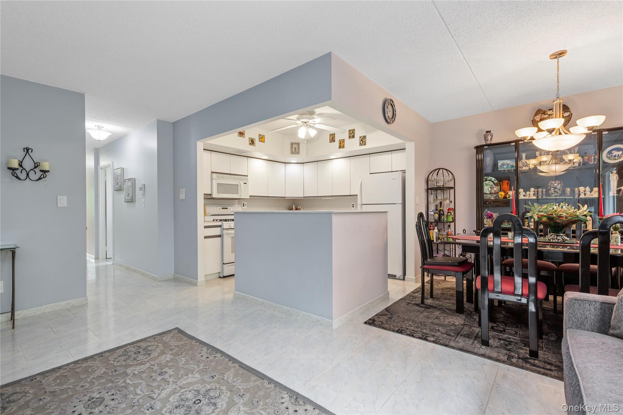 71-28 Sutton Place, Unit 3 Queens, NY 11365 - Photo 8 of 23 Kitchen featuring white appliances, a chandelier, white cabinetry, a ceiling fan, and hanging light fixtures