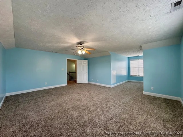 a view of an empty room with a chandelier fan