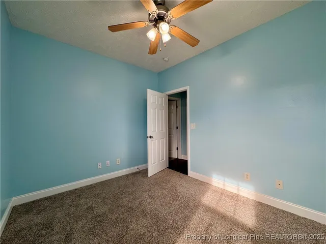 a view of an empty room and chandelier fan