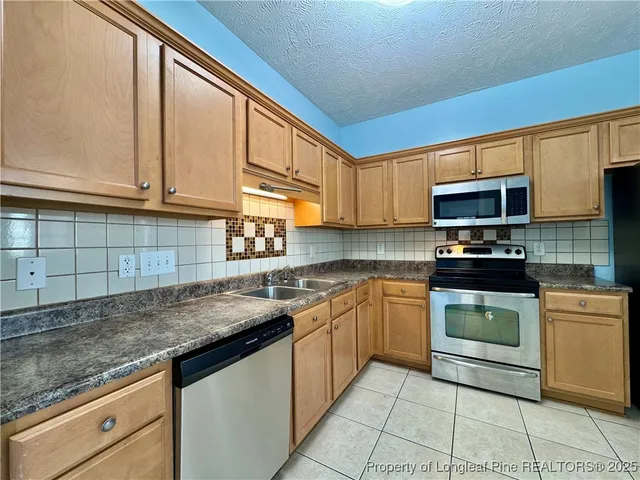 a kitchen with stainless steel appliances granite countertop a sink stove and microwave