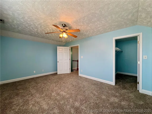 an empty room with a chandelier fan and a bathroom
