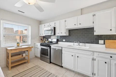 a kitchen with white cabinets sink and appliances