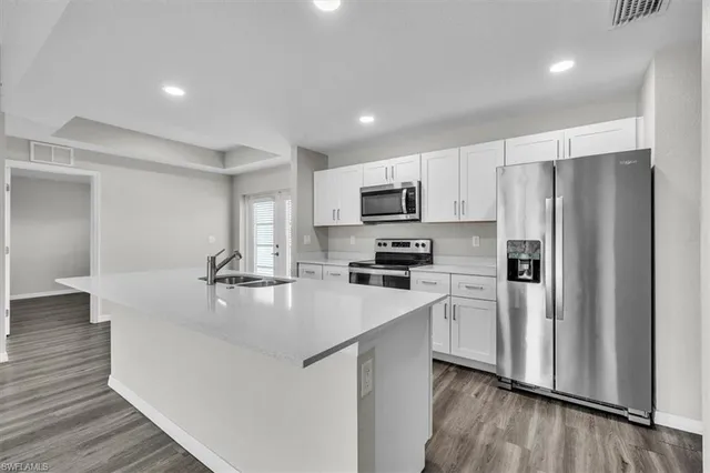 a kitchen with kitchen island a white cabinets a refrigerator a stove and a wooden floor