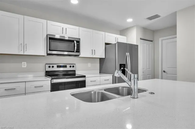 a kitchen with stainless steel appliances granite countertop a sink a stove and a refrigerator