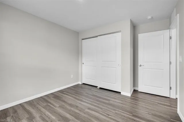 a view of an empty room with wooden floor and closet