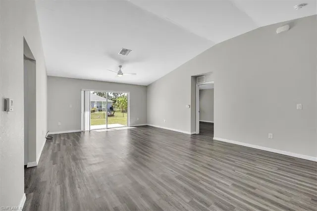 a view of an empty room with window and wooden floor
