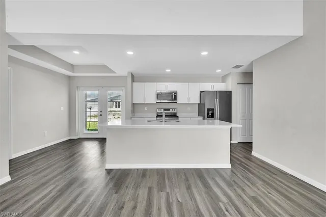 a view of kitchen with stainless steel appliances granite countertop a stove top oven a refrigerator a sink and dishwasher with wooden floor