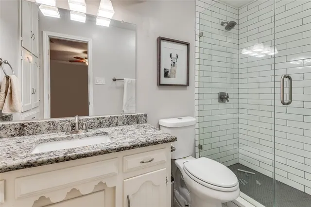 a bathroom with a granite countertop toilet sink and mirror