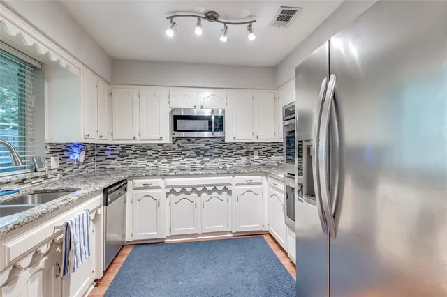 a kitchen with stainless steel appliances granite countertop a refrigerator a stove and a sink