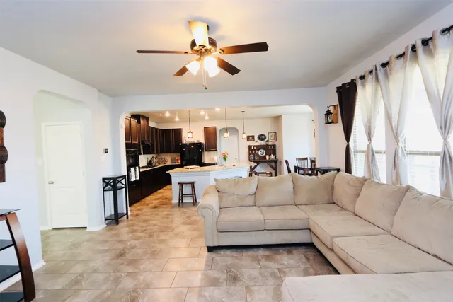 a living room with furniture kitchen view and a large window