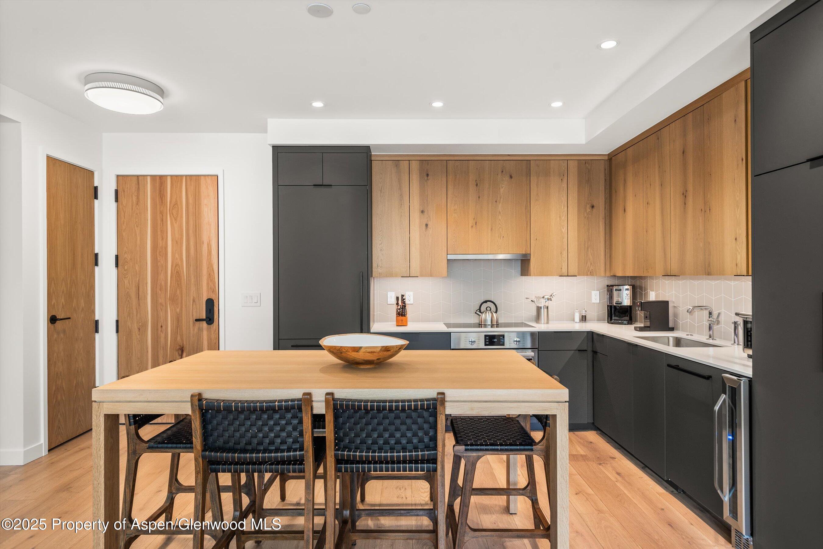 119 Wood Road, Unit 403 Snowmass Village, CO 81615 - Photo 2 of 27 a kitchen with a table chairs sink and cabinets