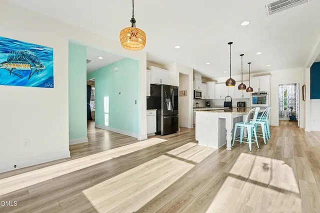 a kitchen with stainless steel appliances granite countertop a stove a refrigerator a oven a kitchen island a table and chairs