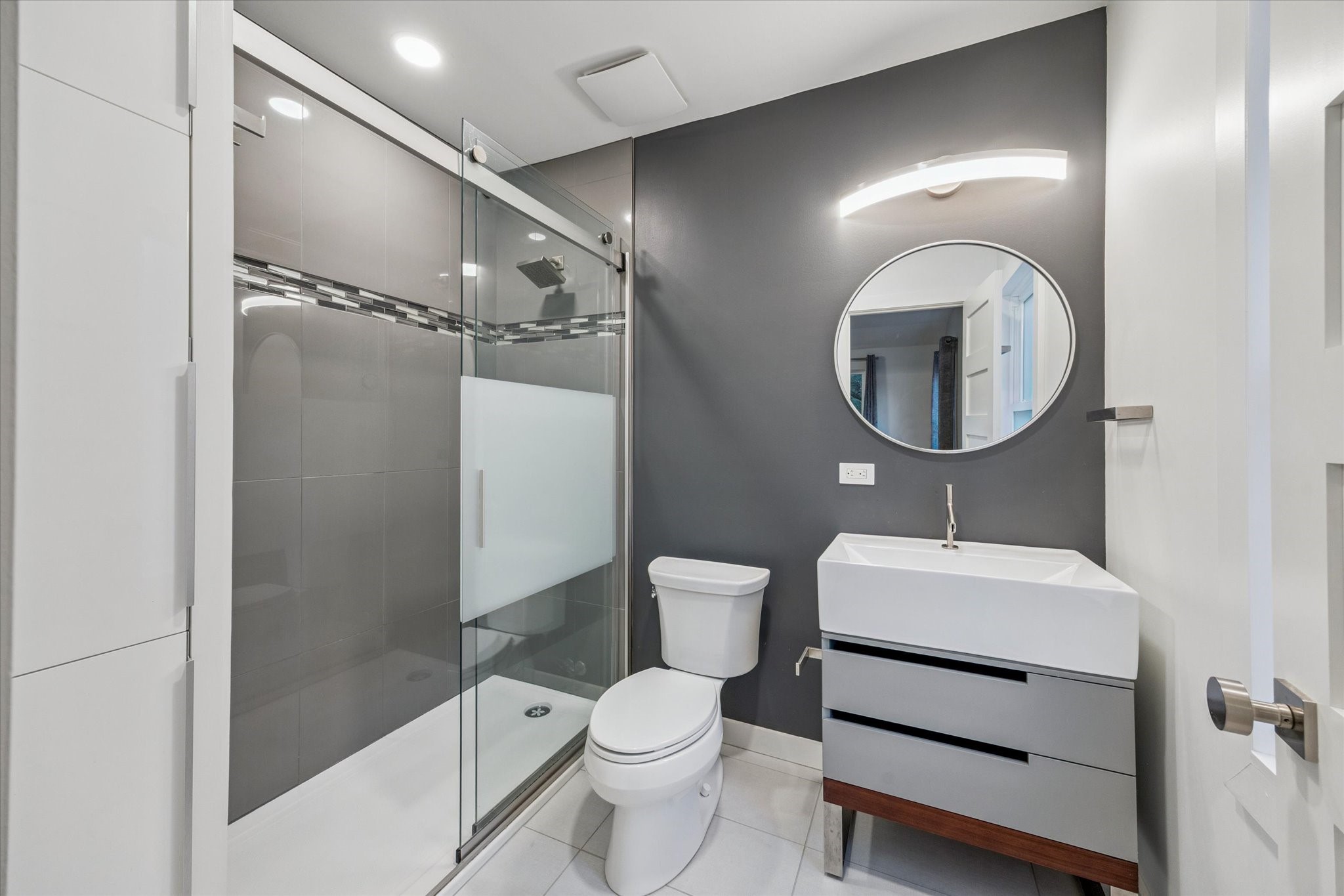 2420 Locke Lane Houston, TX 77019 - Photo 28 of 37 The en-suite bathroom for Secondary Bedroom #3 features tile floors, European cabinetry for linen storage and shower with tile surround and sliding glass door.
