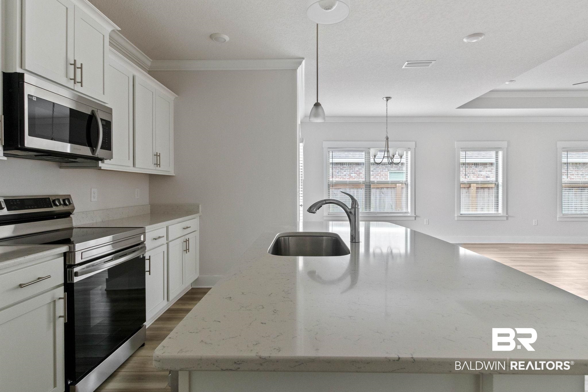 1710 Grouse Street Foley, AL 36535 - Photo 26 of 76 Kitchen island with integrated sink and chrome faucet, featuring light-toned countertops and pendant lighting