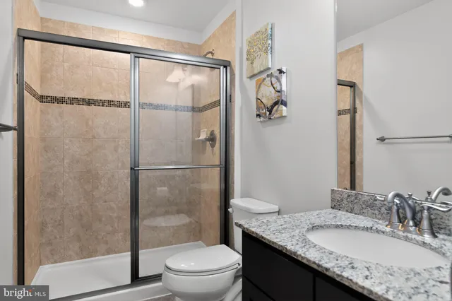 a bathroom with a granite countertop sink toilet and shower