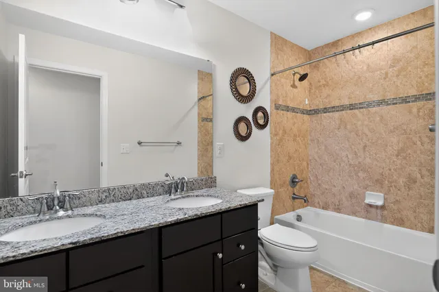 a bathroom with a granite countertop sink mirror vanity and toilet