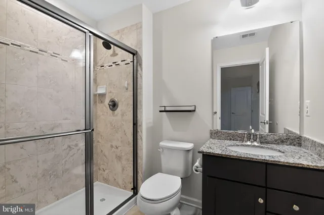 a bathroom with a granite countertop sink toilet and shower