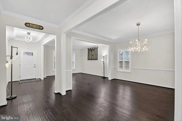 a view of a room with wooden floor chandelier and windows