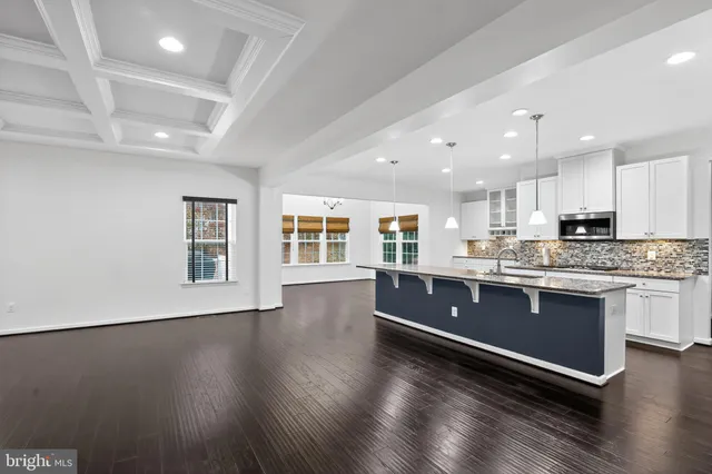 a large kitchen with stainless steel appliances granite countertop a stove a sink a refrigerator white cabinets and wooden floor