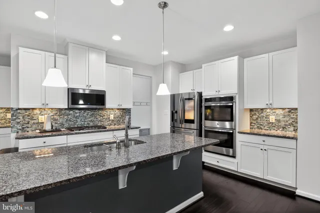 a kitchen with stainless steel appliances kitchen island granite countertop a sink a stove and cabinets