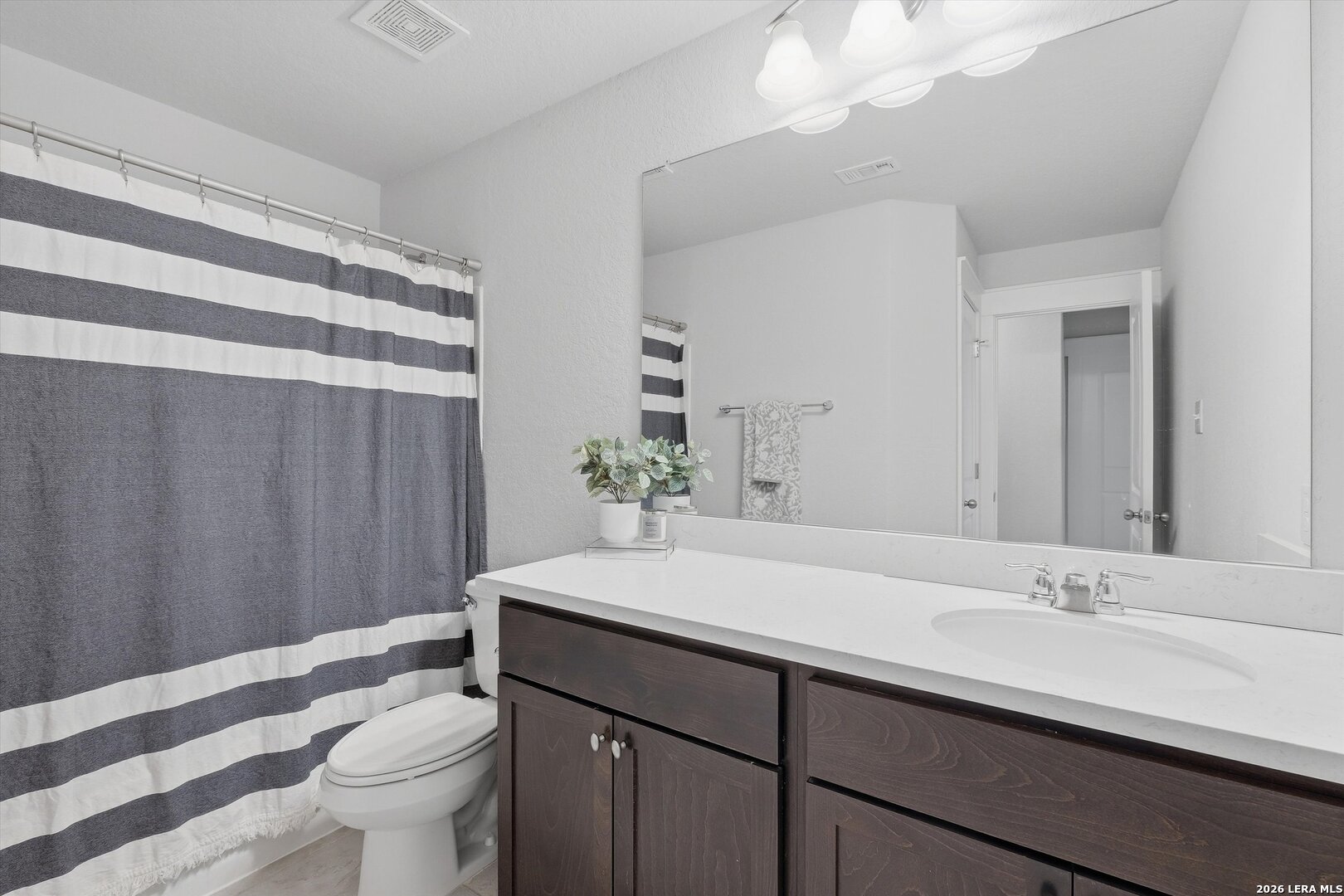 10776 Rosalina Loop Converse, TX 78109 - Photo 25 of 31 a bathroom with a sink a toilet a mirror and shower curtain