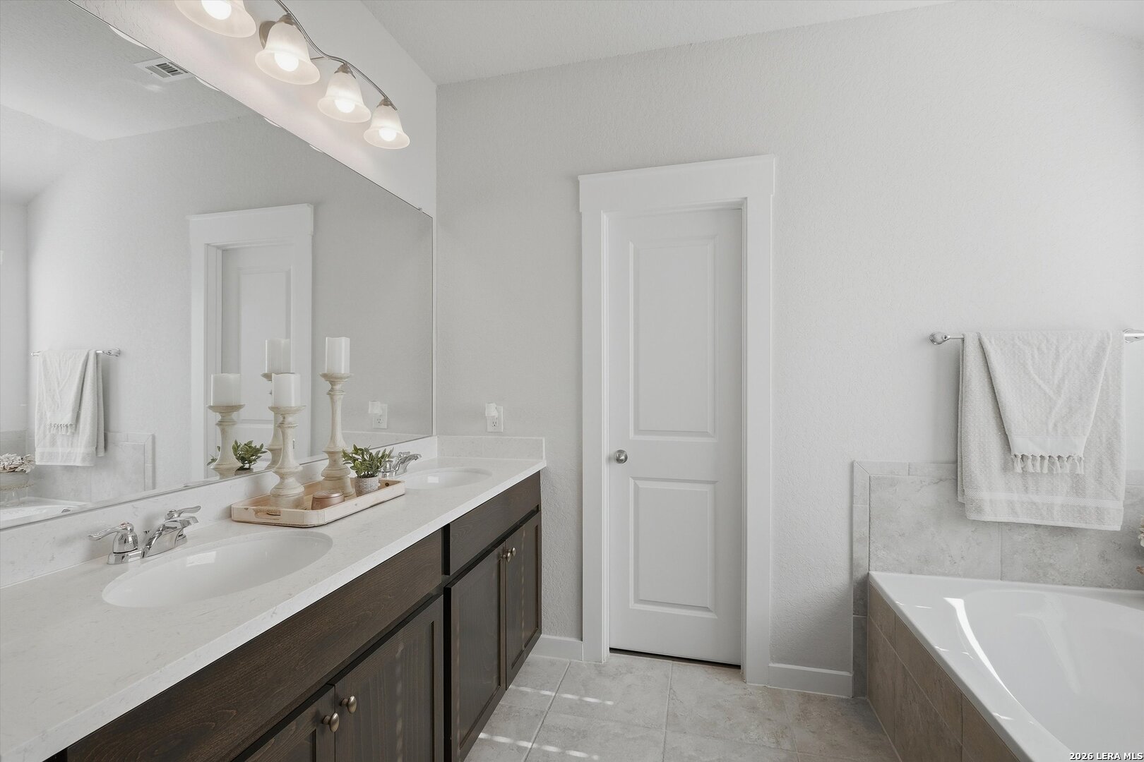 10776 Rosalina Loop Converse, TX 78109 - Photo 26 of 31 a bathroom with a double vanity sink a mirror and a bathtub
