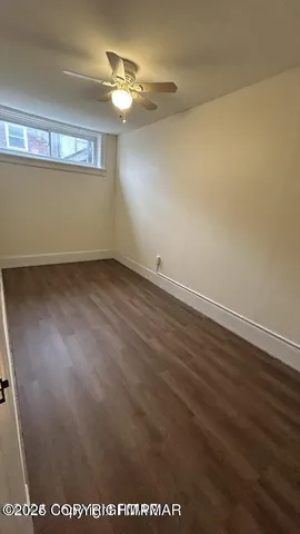a view of an empty room with wooden floor and cabinet