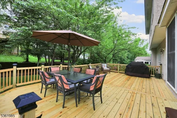 a view of a roof deck with table and chairs under an umbrella with wooden floor and fence