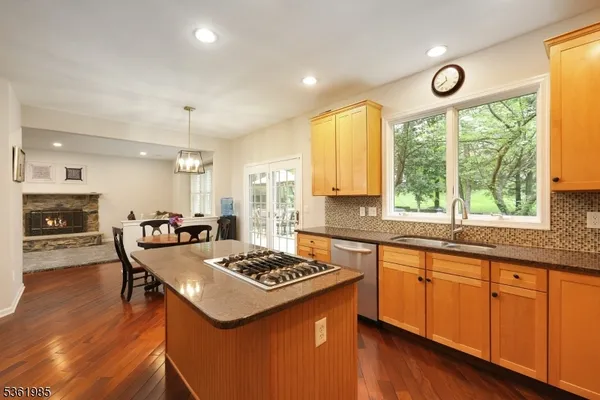 a kitchen with a stove a sink dishwasher a refrigerator and a dining table with wooden floor