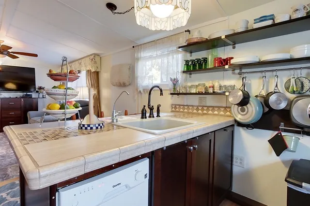 a kitchen with a sink a stove and chairs with wooden floor