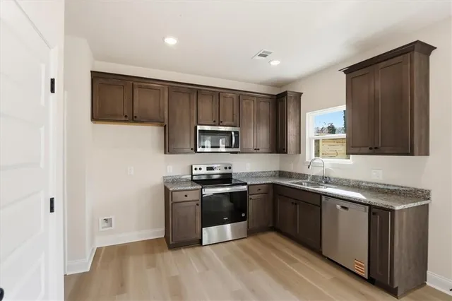 a kitchen with stainless steel appliances granite countertop a sink stove and refrigerator