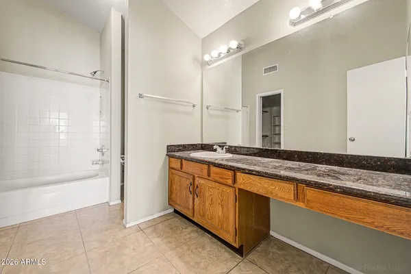 a bathroom with a granite countertop double vanity sink a mirror and a bathtub
