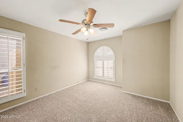 an empty room with windows and ceiling fan