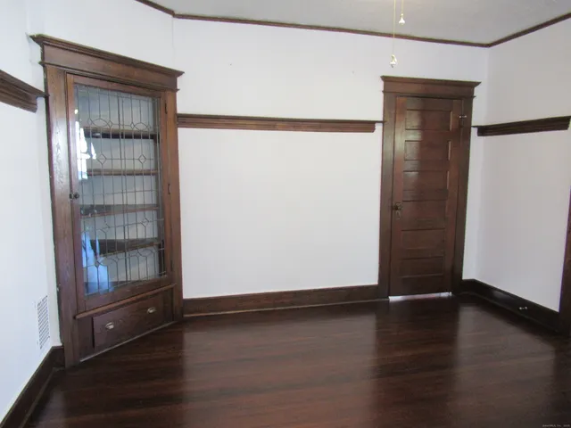 an empty room with wooden floor cabinet and door